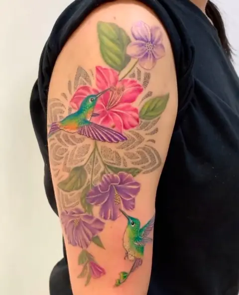 Tatuaje de colibríes y flores a color en el brazo